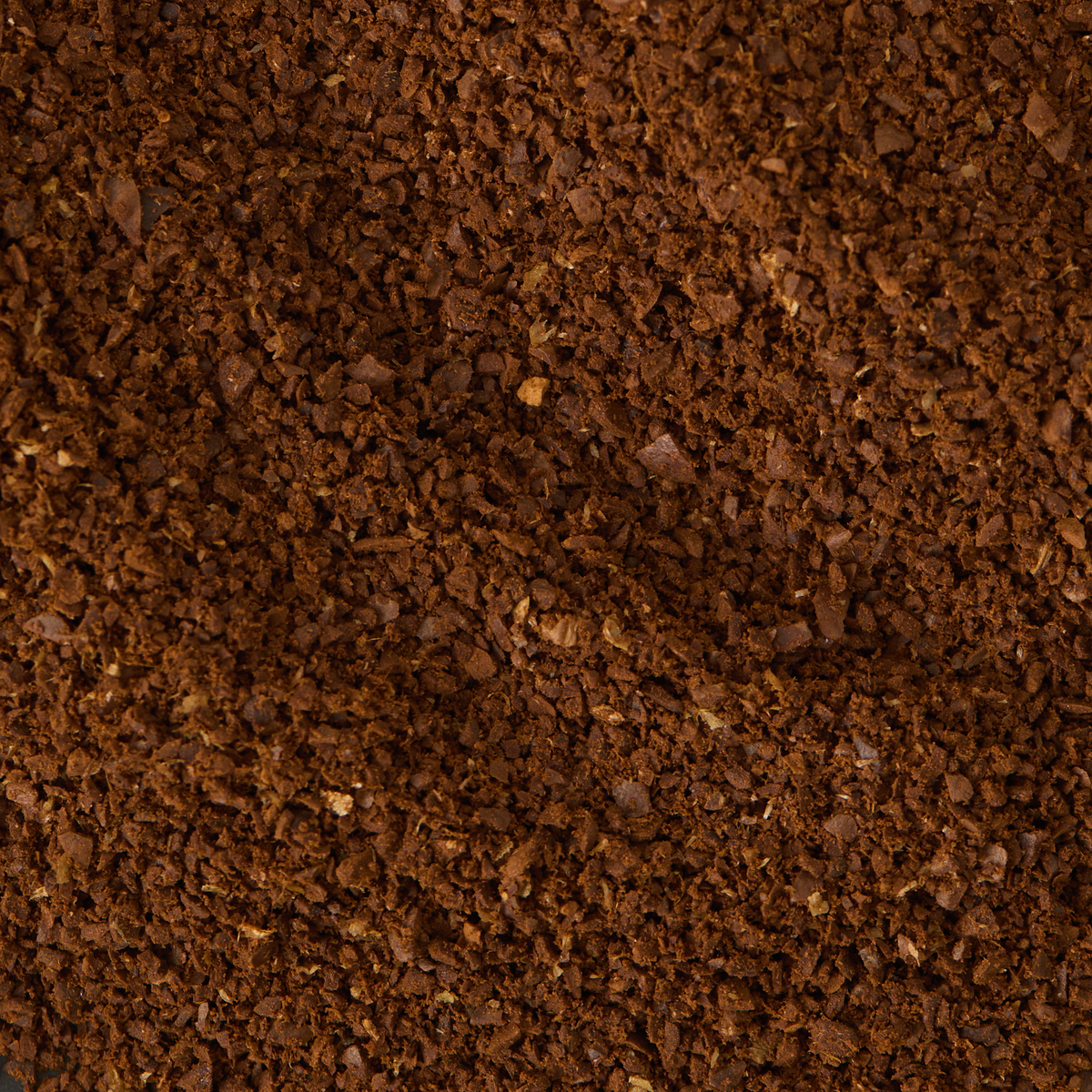 Close-up view of a pile of Jamaica Blue Mountain Coffee, revealing its dark brown, crumbly texture and small, uneven granules—crafted from hand-picked beans.