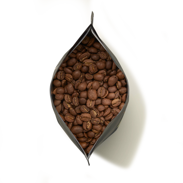 An open black bag of Jamaica Blue Mountain Coffee, filled with whole, hand-picked beans and viewed from above on a white background.