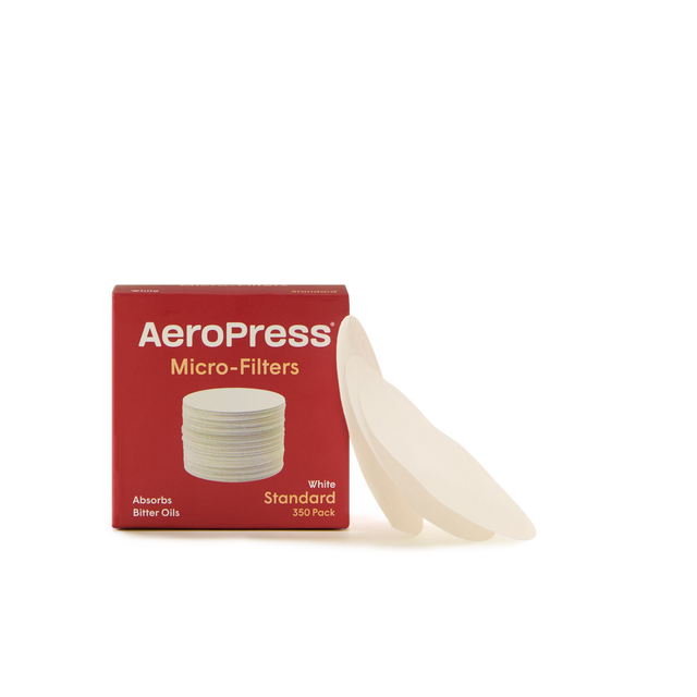 A red box labeled AeroPress Micro-Filters sits on a white background, with several white circular coffee filters leaning against it.