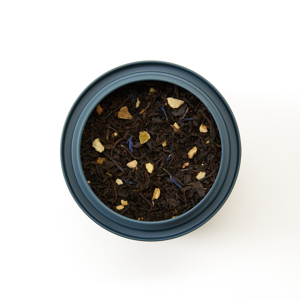 A round tin of Earl Grey Loose Leaf Tea, filled with dark tea leaves and small pieces of dried fruit or citrus peel, viewed from above on a white background.