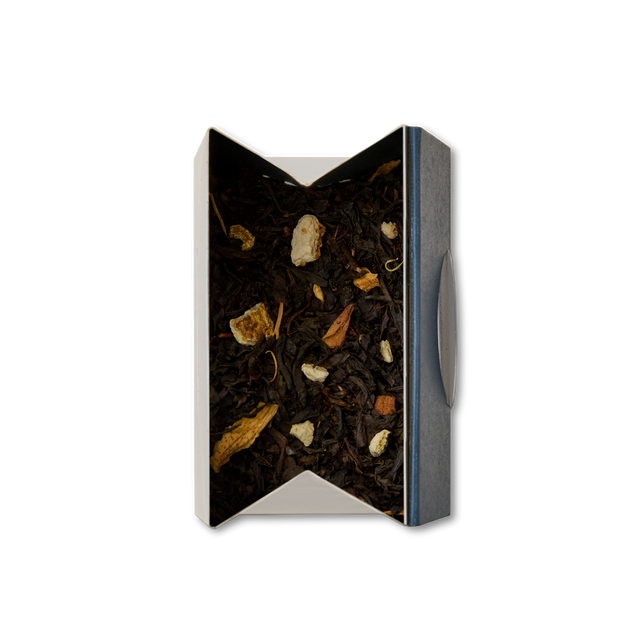 An open box of Orange Blossom Loose Leaf Tea viewed from above, revealing a blend of black tea mixed with dried fruit, orange blossom, and herbs inside. The white box features a dark-colored side panel and a partially visible flap on the right.