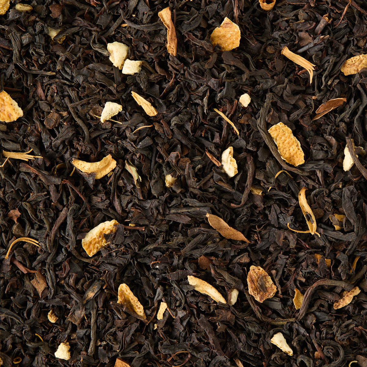 A close-up of Orange Blossom Loose Leaf Tea, featuring black tea leaves blended with small, irregular pieces of dried orange peel scattered throughout, creating a vibrant blend reminiscent of floral black tea.