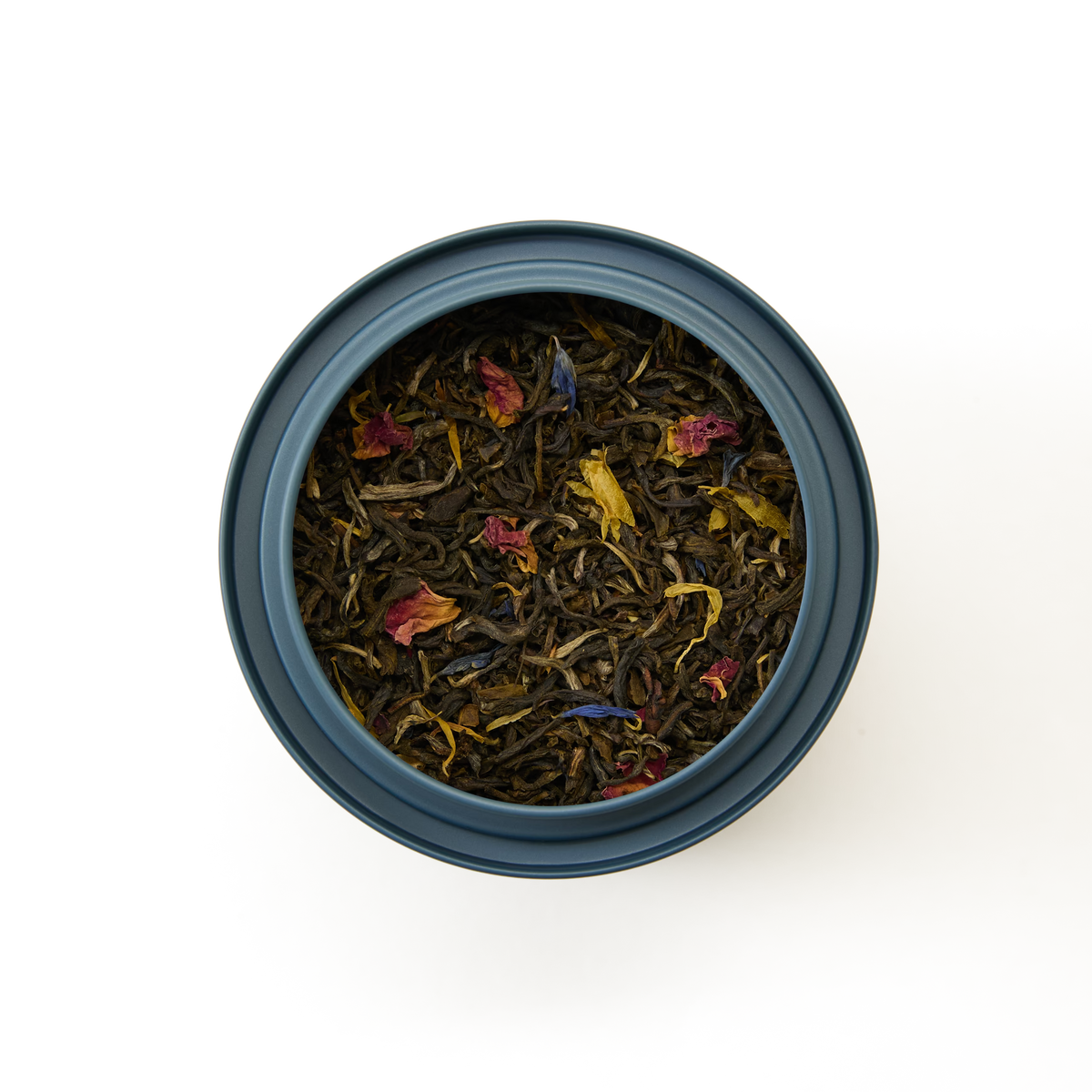 A round container filled with Extravagant Earl Grey Loose Leaf Tea, featuring loose leaf tea blended with dried flower petals in various colors, viewed from above on a white background.