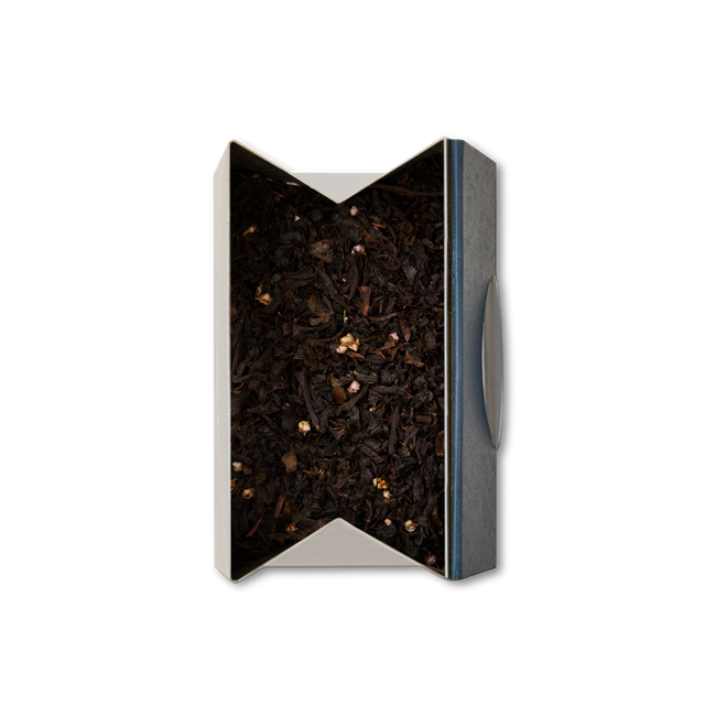 A rectangular box, open at the top and viewed from above on a white background, is filled with Whisky Loose Leaf Tea—dark Scottish black tea leaves mixed with small, light-colored pieces reminiscent of heather flowers.