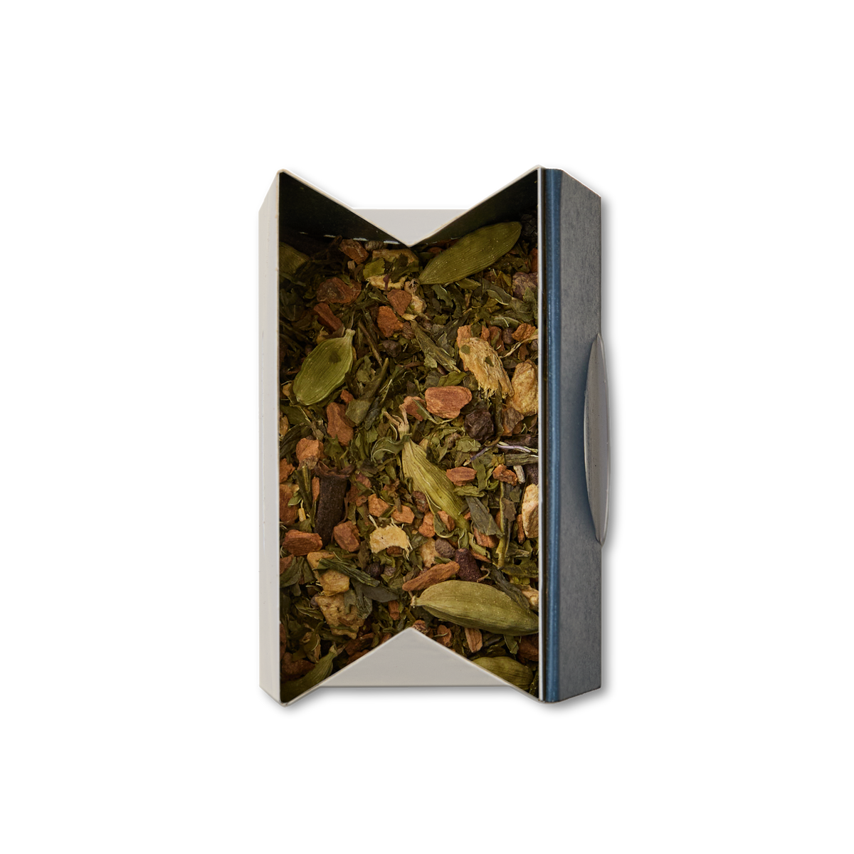 An open rectangular box of Shanghai Chai Loose Leaf Tea filled with cardamom pods and assorted dried spices, viewed from above on a white background.