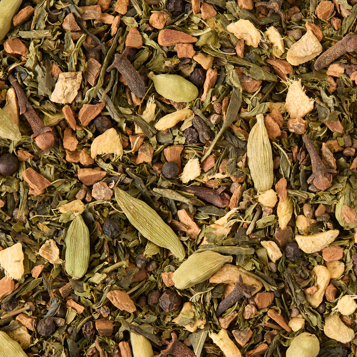 A close-up view of Shanghai Chai Loose Leaf Tea reveals a vibrant blend of loose dried green tea leaves, cardamom pods, cloves, peppercorns, and pieces of dried ginger—ideal for crafting a fragrant spiced green tea or an invigorating chai blend.