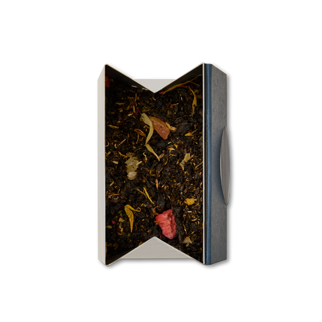 A rectangular box of Garden Party Oolong Loose Leaf Tea, viewed from above on a white background, with the blend visible inside—dried black leaves mixed with colorful pieces like red and yellow petals.