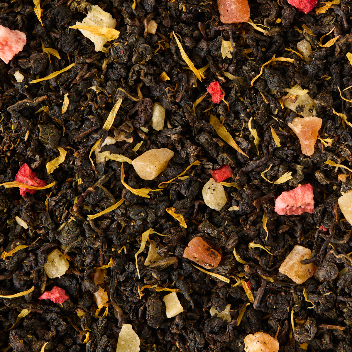 Garden Party Oolong Loose Leaf Tea features a blend of dark oolong tea leaves, dried fruit pieces, and yellow petals, viewed in close-up to highlight its diverse textures and vibrant colors.