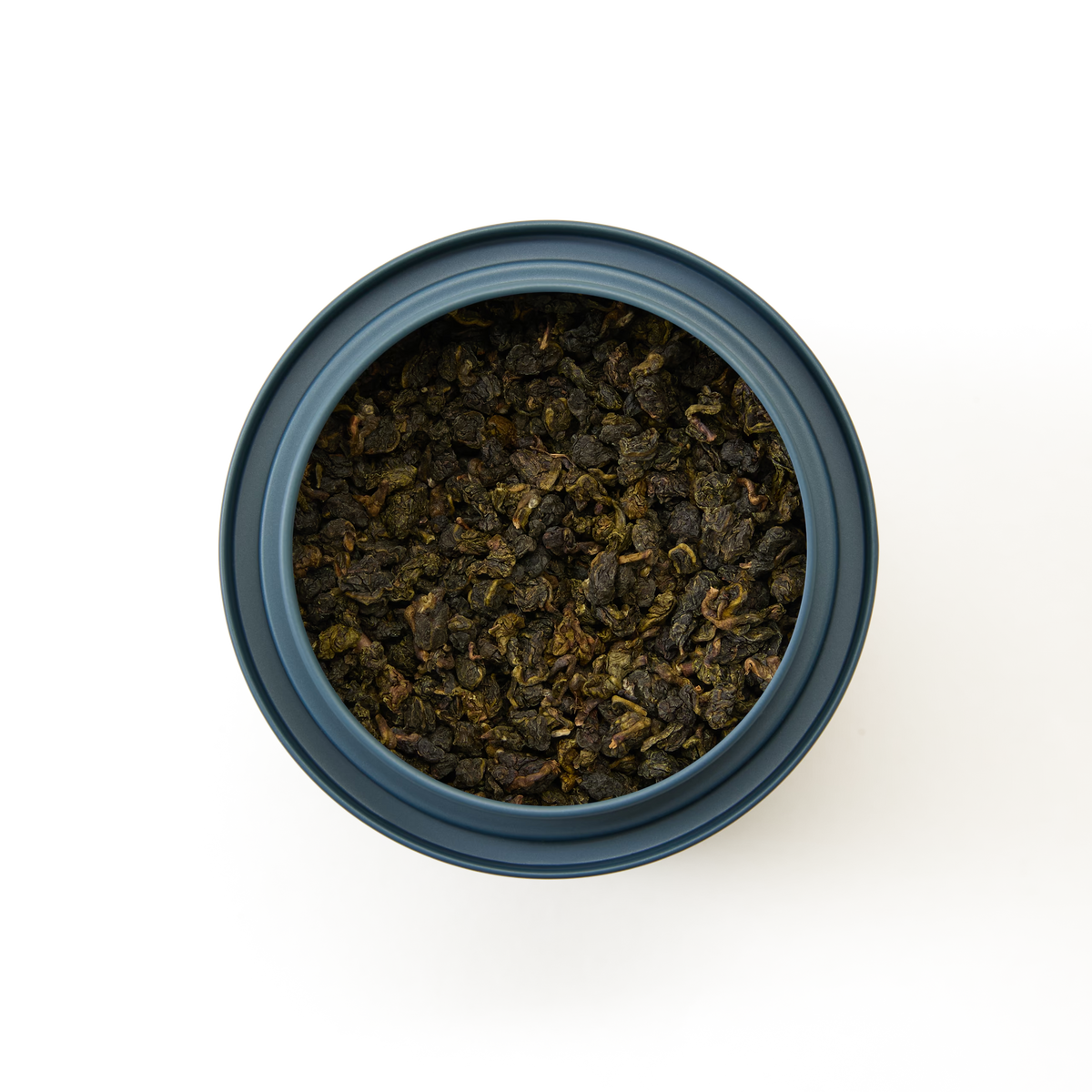 A top-down view of a blue tin filled with Jade Oolong Loose Leaf Tea, highlighting the rich, aromatic textures of this Taiwanese oolong, set against a white background.