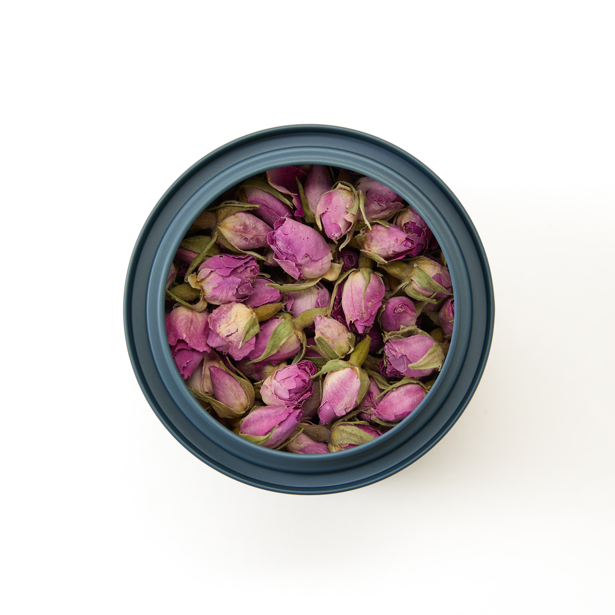 A round dark container of Rosebuds Loose Infusion, filled with whole pink buds, viewed from above on a plain white background—perfect for brewing a delicate floral tea.