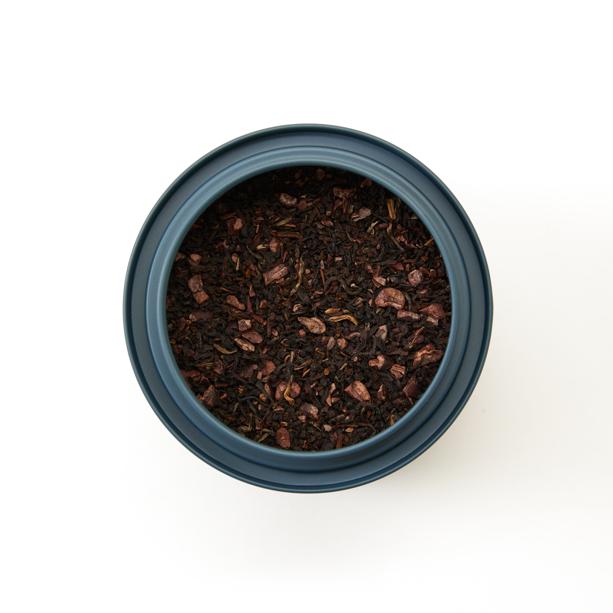A blue container of Dark Chocolate Loose Leaf Tea, a rich sugar-free blend of black tea and cocoa nibs, viewed from above against a white background.