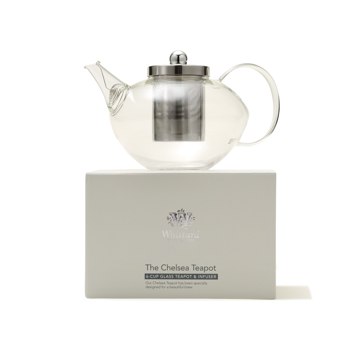 A Chelsea Glass Teapot with Infuser, featuring a clear borosilicate glass body and a metal infuser and lid, is displayed on a white box labeled "The Chelsea Teapot" from Whittard against a plain white background.