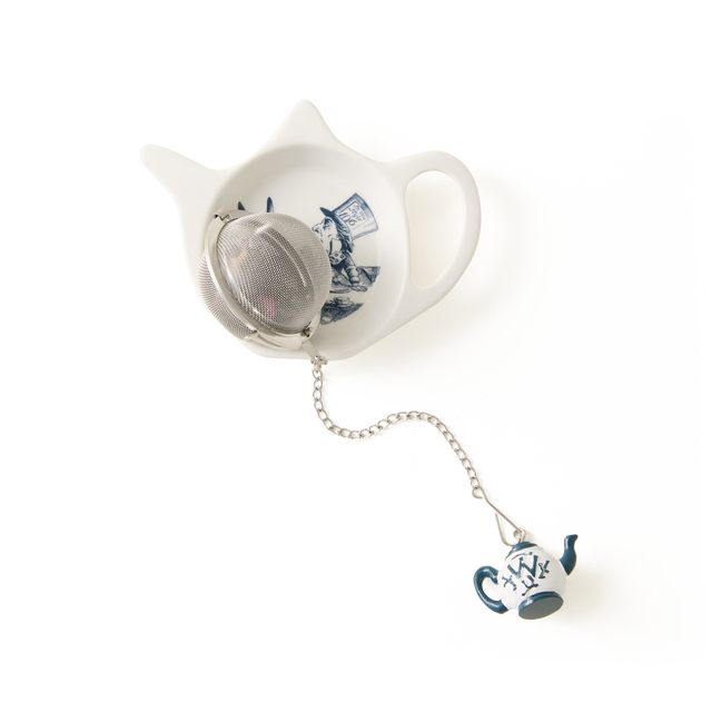 A metal tea infuser with a small teapot charm rests on the Alice in Wonderland Tea Tidy—a white, cat-shaped piece from the Alice Collection, adorned with blue artwork and set against a plain white background.