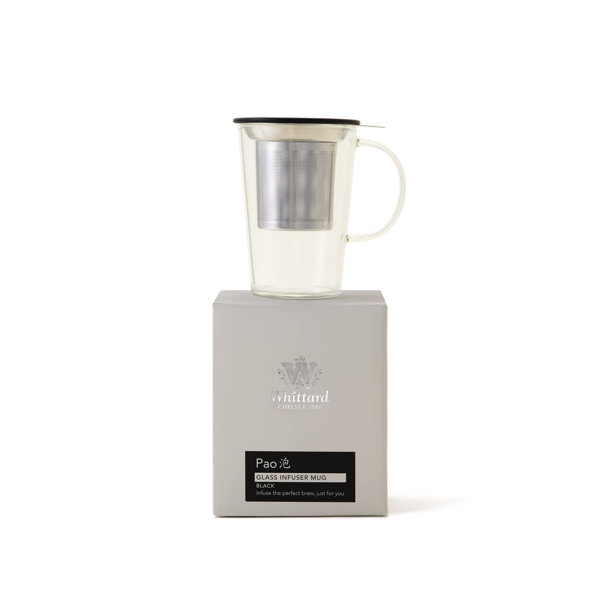 A clear glass mug with a metal infuser and black lid sits on top of a light gray box labeled Pao Glass Infuser Mug from Whittard of Chelsea. The background is plain white.