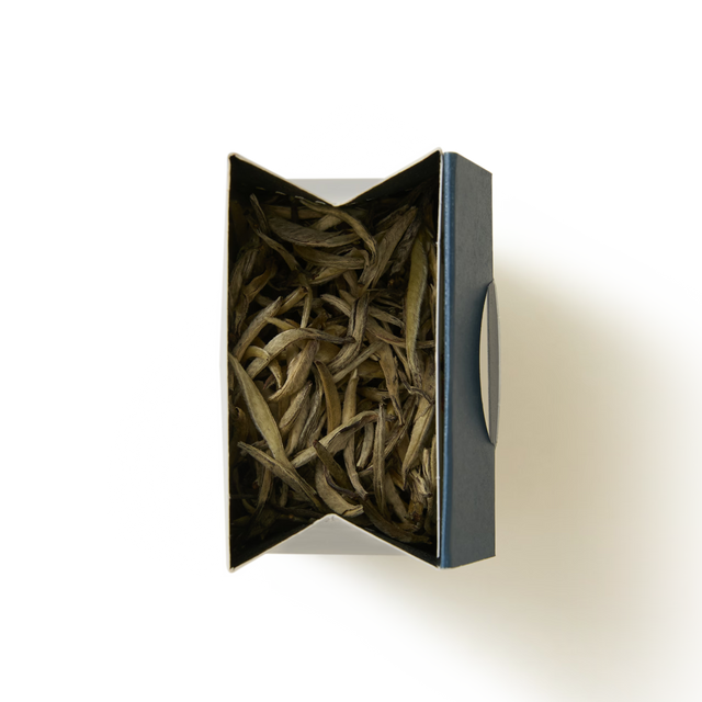 An open rectangular box filled with slender, dried Silver Needle Loose Leaf Tea leaves.
