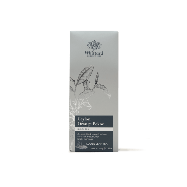 A box of Ceylon Orange Pekoe Loose Leaf Tea, adorned with a silver-gray design featuring a botanical illustration and detailed text describing this classic Sri Lankan tea variety along with its net weight.