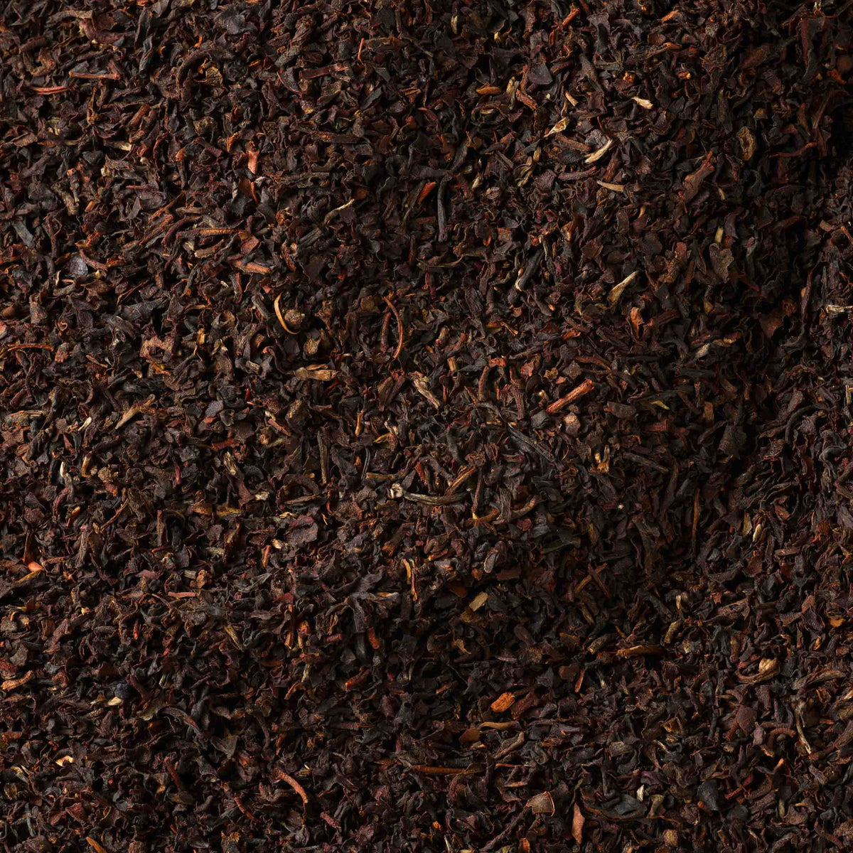 A close-up view of English Breakfast Loose Leaf Tea, featuring finely chopped leaves in a deep brown hue with lighter brown flecks—this single origin blend from West Java delivers an authentic English Breakfast tea experience.