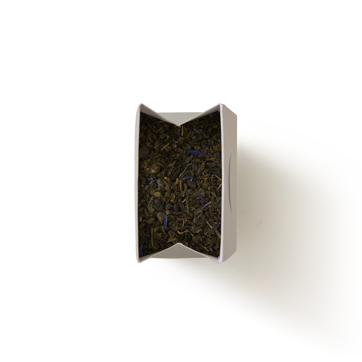 A top-down view of an open rectangular box filled with Marrakech Mint Loose Leaf Tea, displaying dark tea leaves and purple flower petals, set against a plain white background.