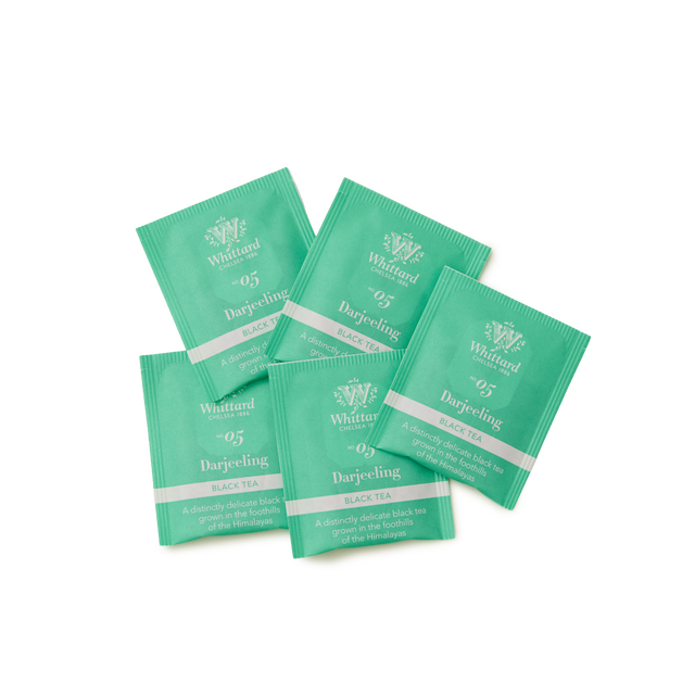 Five green Whittard Darjeeling black tea sachets are spread out on a white background, each labeled 05 Darjeeling with white and silver text.