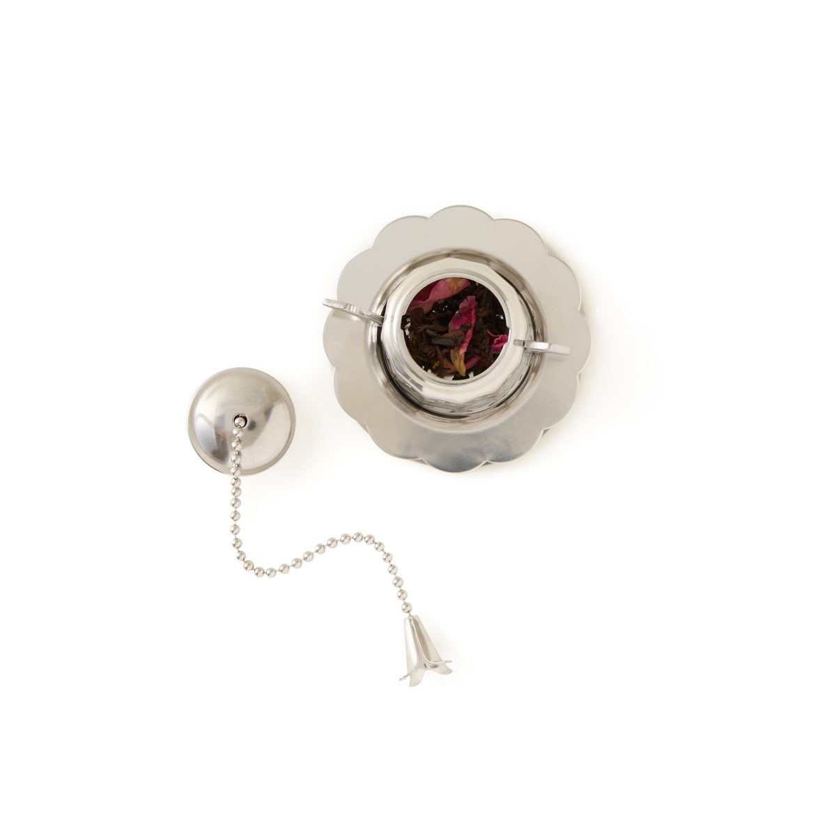 The Tea Party Infuser, filled with loose leaf tea, rests on a round saucer against a white background.