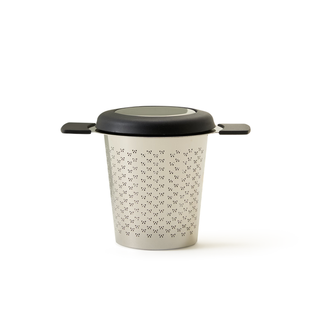 The Mug Infuser is a stainless steel tea infuser with handles on both sides and a black lid, featuring a pattern of small holes—making it the perfect accessory for brewing your favorite loose leaf tea.