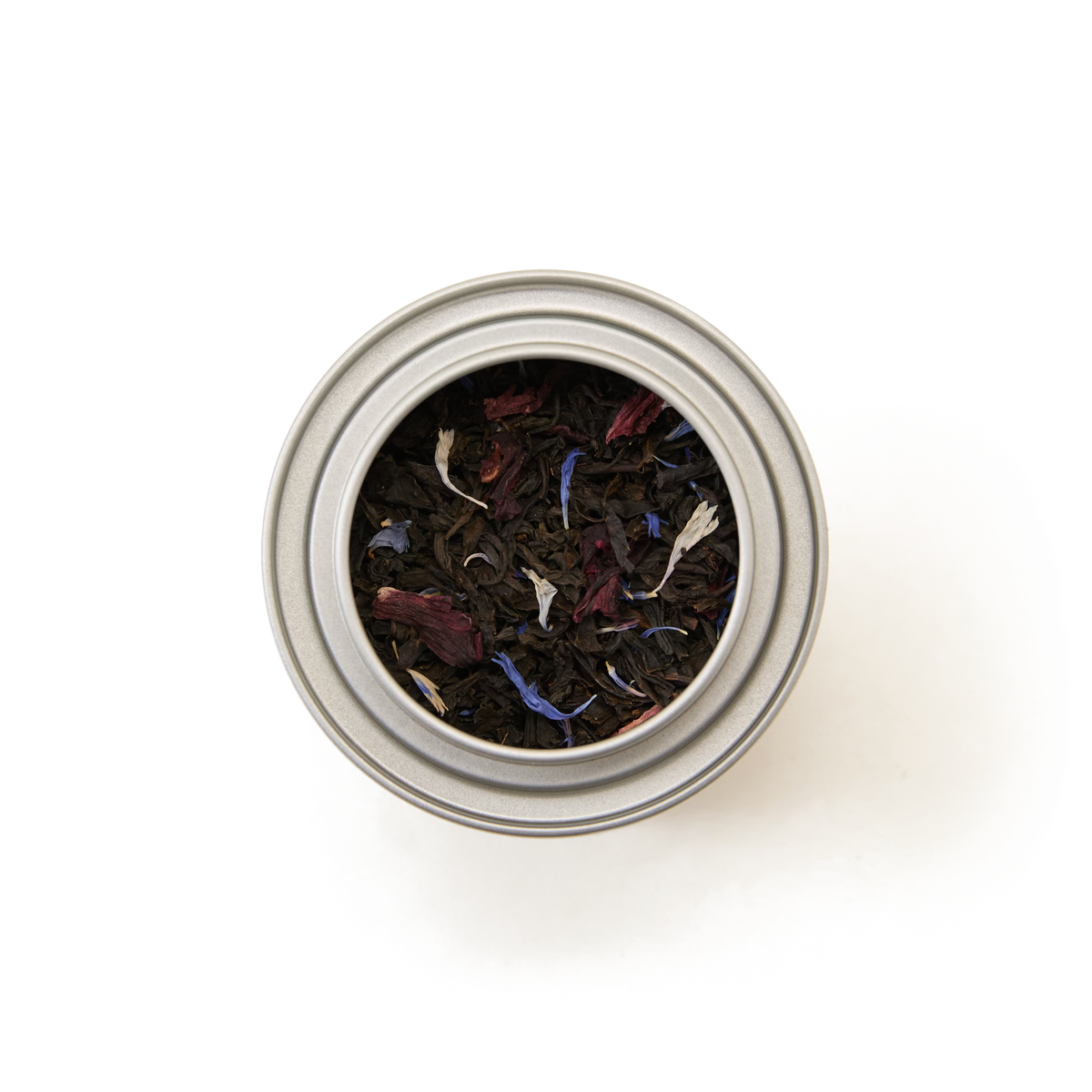A top view of the Piccadilly Blend Loose Leaf Mini Caddy, a silver tin filled with loose leaf black tea blended with colorful flower petals, creating a vibrant floral tea mix against a white background.