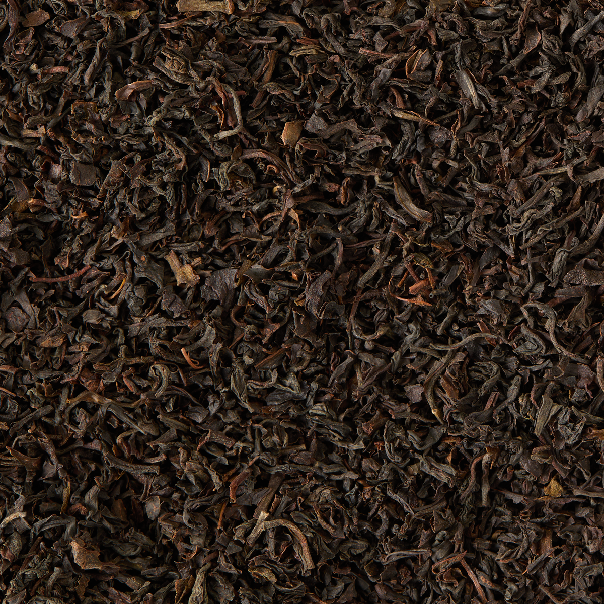 A close-up view of loose, dry Chelsea Breakfast Loose Leaf Mini Caddy tea leaves, a traditional British breakfast blend featuring a rich combination of Sri Lankan and Kenyan teas, spread out evenly.