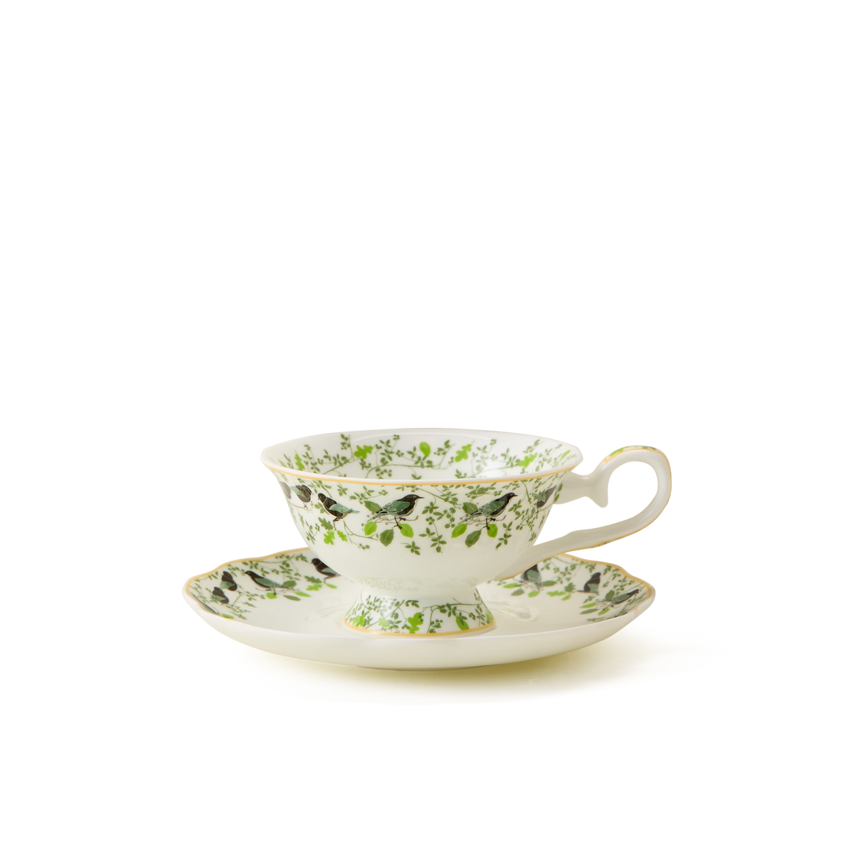 A delicate white teacup with a matching saucer, both decorated with green leaves and small black birds, accented by gold trim, set against a plain white background.