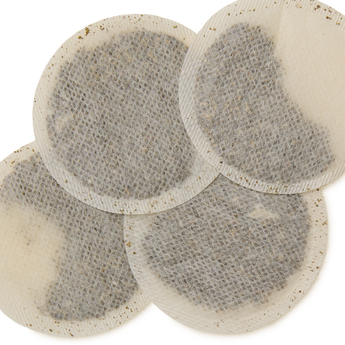 Four round Mango & Bergamot Teabags with visible tea leaves inside, overlapping each other on a white background—perfect for brewing a refreshing cup of tropical green tea.