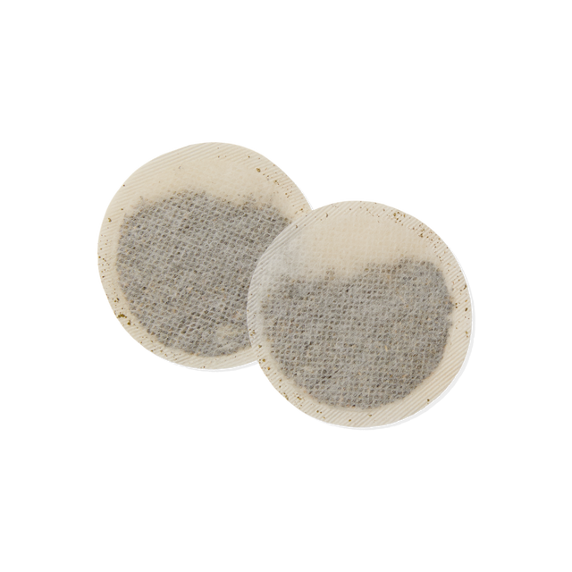 Two round, flat Jasmine Teabags with a mesh-like texture, filled with dark tea leaves, lying overlapping on a white background.