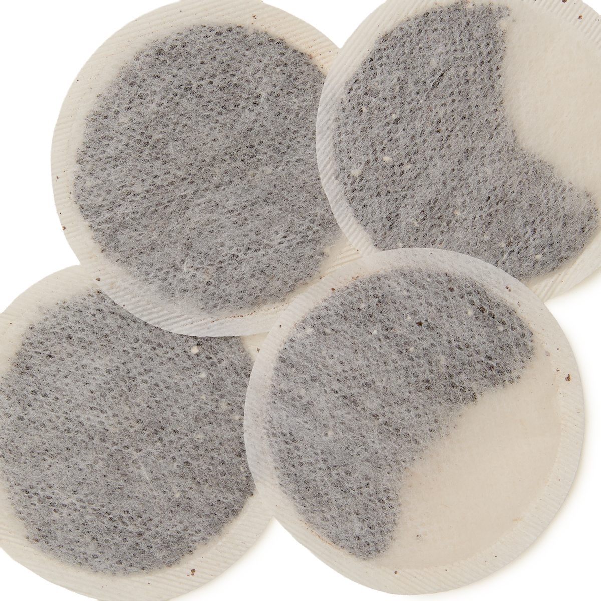 Four round, flat English Rose Teabags with visible dark tea leaves inside are overlapping each other on a white background.