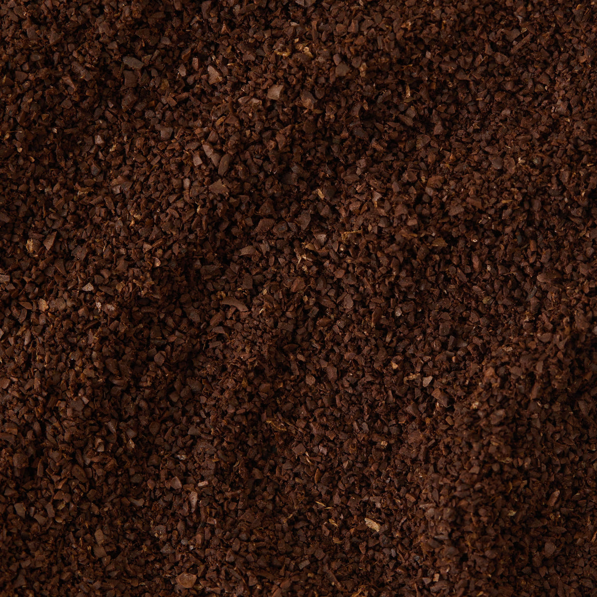 A close-up view of dark brown, finely ground Guatemala Elephant Coffee, highlighting the small, textured granules densely packed together.