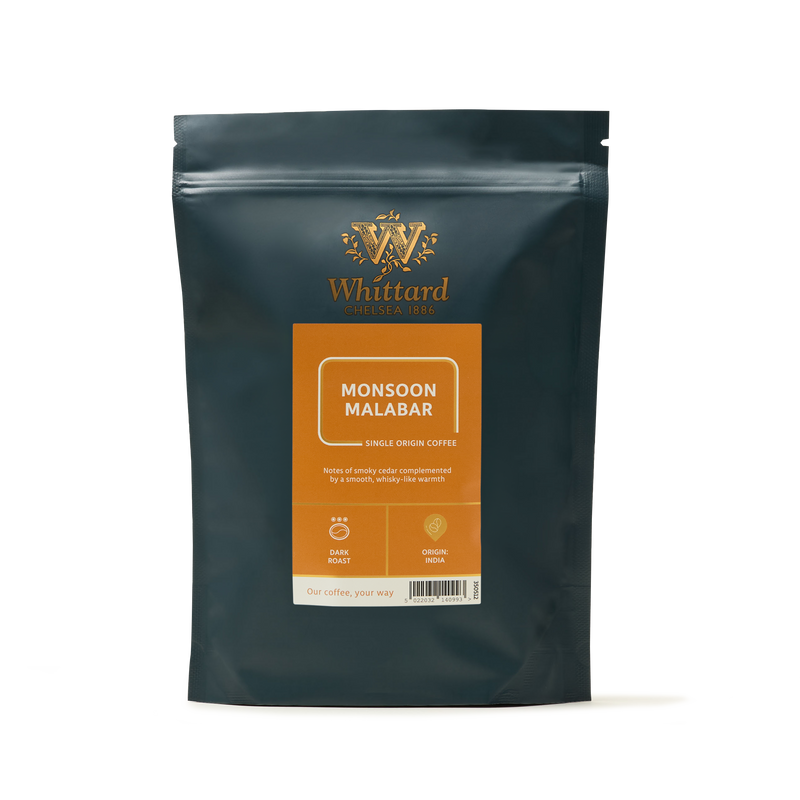 A dark green bag of Monsoon Malabar Coffee with an orange label, featuring tasting notes and the brand logo on the front.