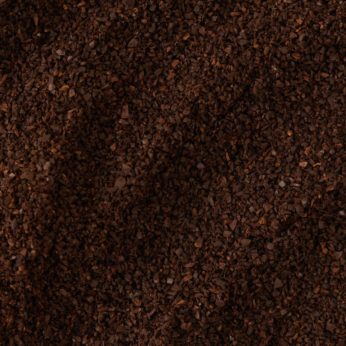Close-up of a pile of ground Monsoon Malabar Coffee, highlighting its dark brown color and coarse texture.