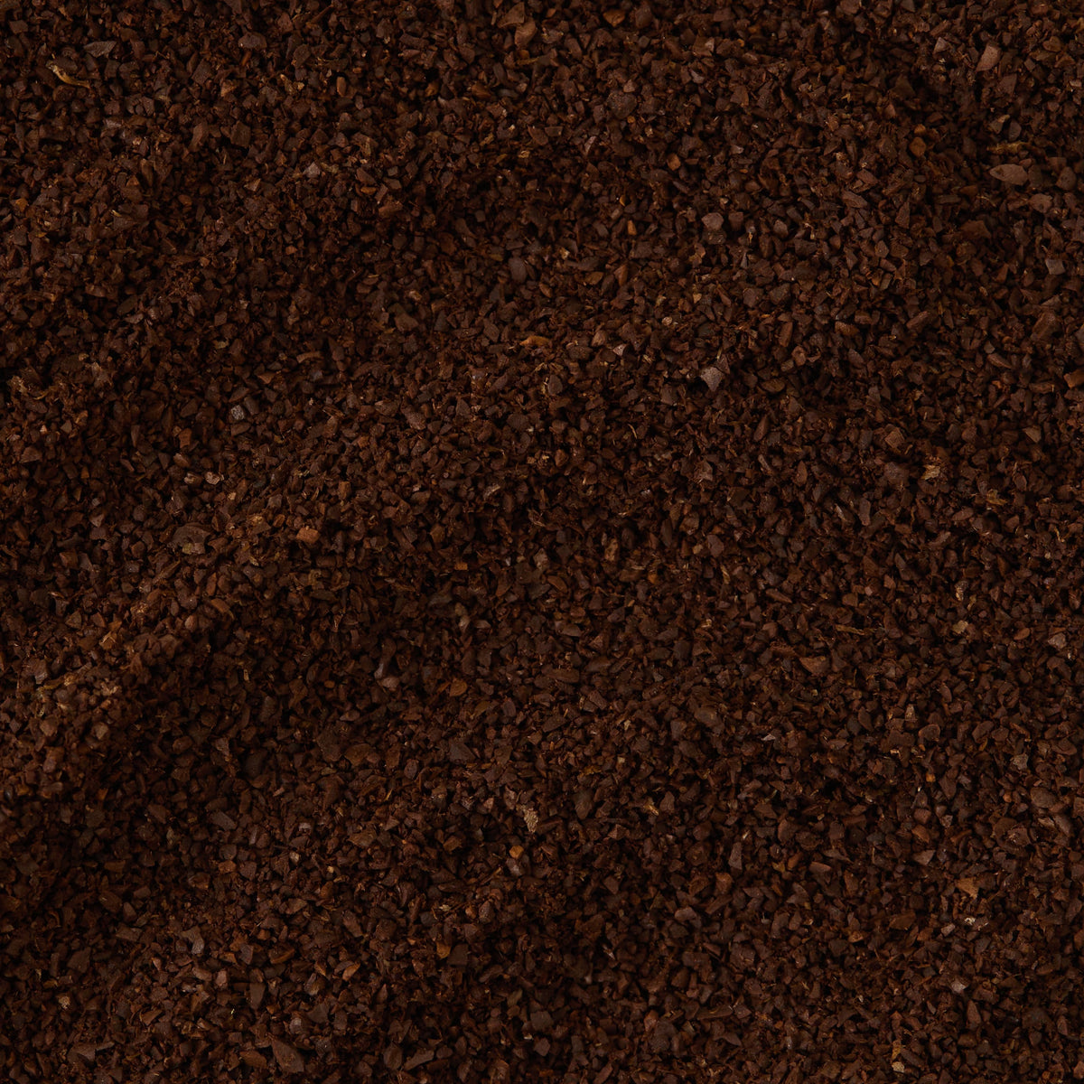 A close-up view of a pile of dark brown, ground San Agustin Colombia Coffee, highlighting the texture and granules of these specialty coffee grounds.
