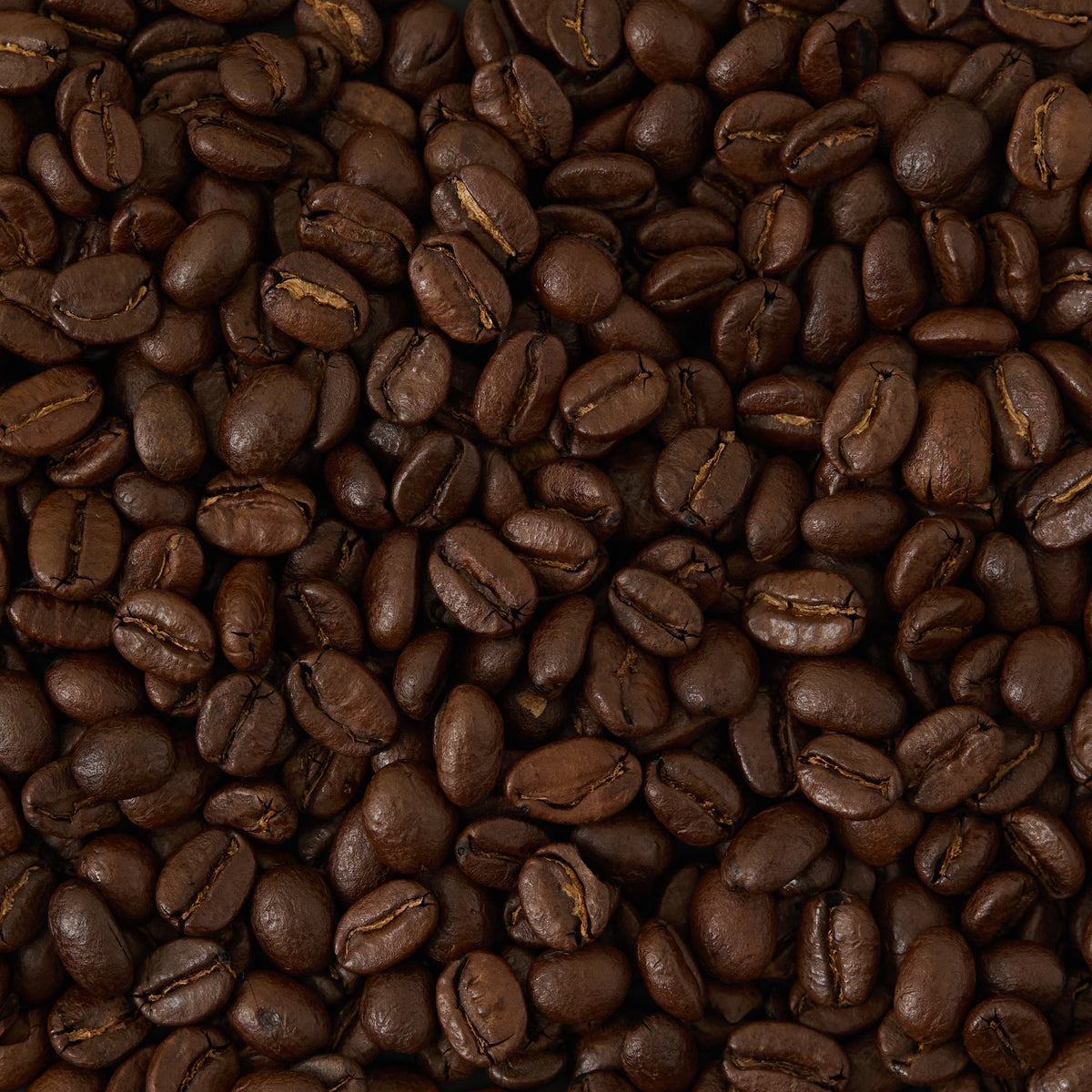 A close-up view of a pile of roasted coffee beans, showing their dark brown color and glossy texture—these are San Agustin Colombia Coffee beans, premium Colombian Arabica sourced from the renowned Huila region.