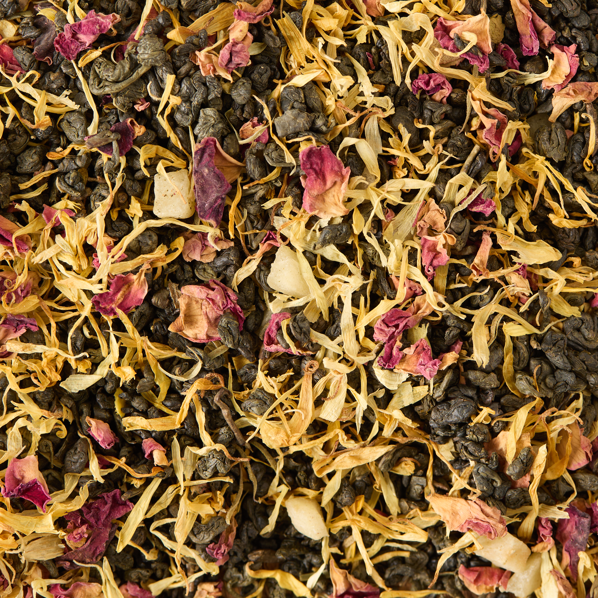 Passionfruit & Mango Loose Leaf Tea is a vibrant green tea blend featuring tightly rolled Gunpowder green tea leaves combined with dried yellow and pink flower petals, resulting in a colorful and textured appearance.