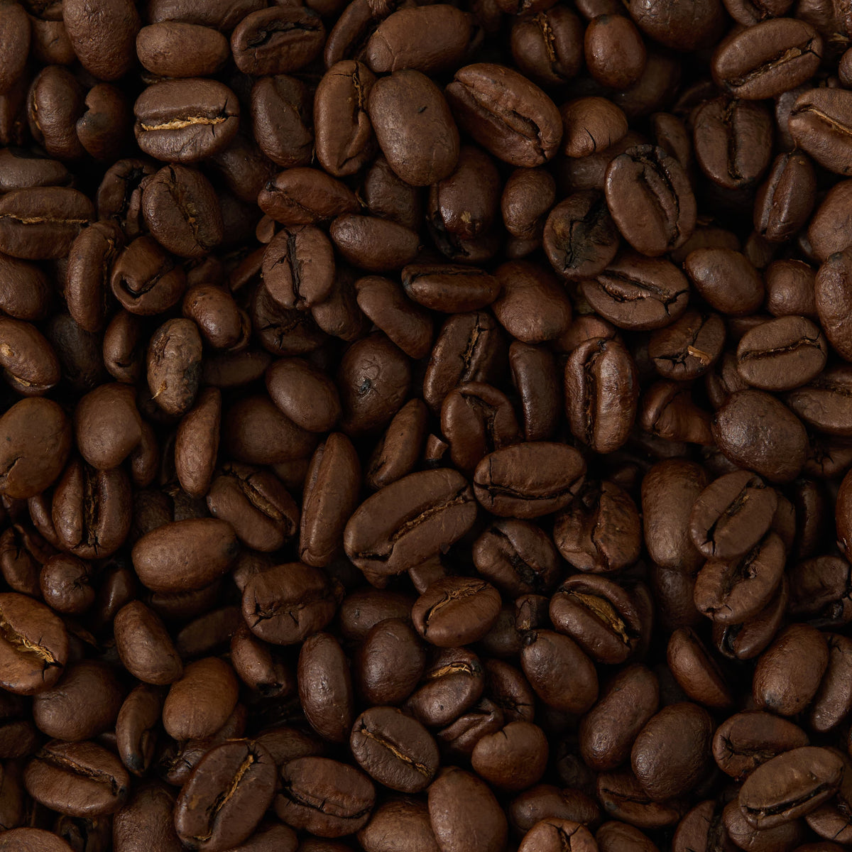 A close-up view of a pile of dark roasted Breakfast Blend Coffee beans, showcasing their glossy surface and rich brown color—perfectly complementing a celebrated teas gift set that features individually wrapped teabags, including classic English Breakfast tea.