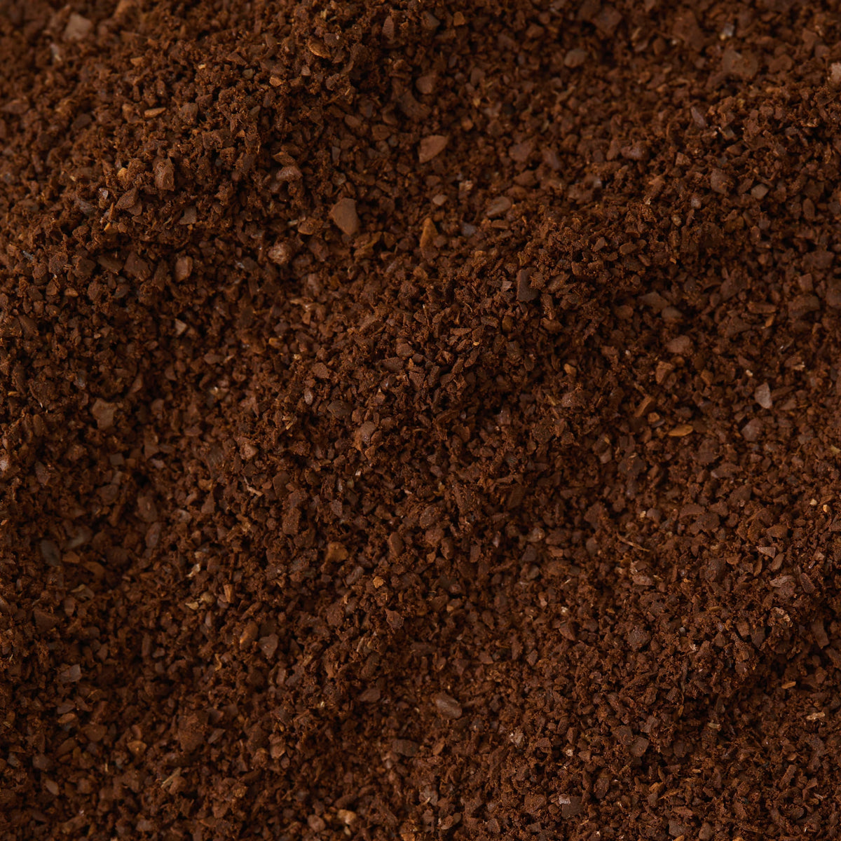 Close-up of a pile of Breakfast Blend Coffee, showcasing its coarse texture and rich, dark brown color as it fills the entire frame—an inviting sight for coffee lovers and the perfect companion to a celebrated teas gift set or English Breakfast tea for a complete morning ritual.