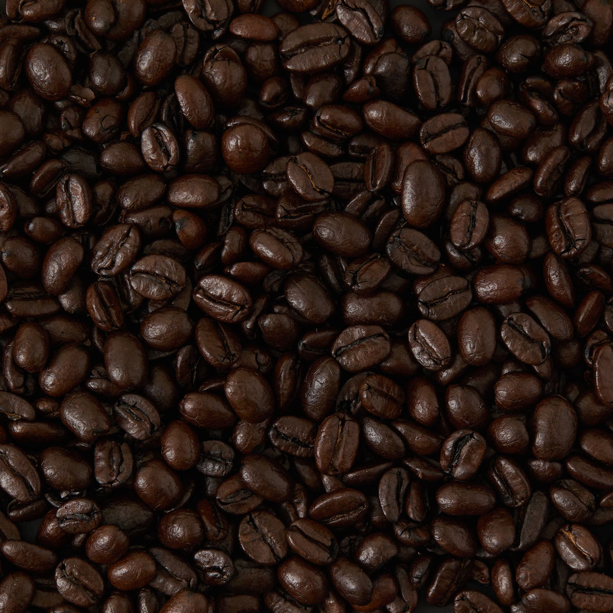 A close-up view of Whittard House Blend Coffee beans, highlighting their shiny, dark brown surfaces tightly packed together.