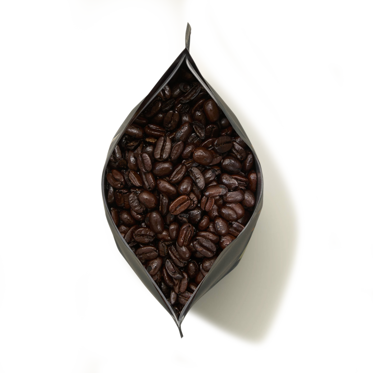 A top view of an open black bag of Old Brown Java Coffee filled with dark roasted coffee beans, set against a plain white background.