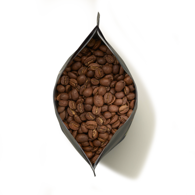 A top-down view of an open bag of Kenya Peaberry Coffee filled with whole beans, set against a white background.