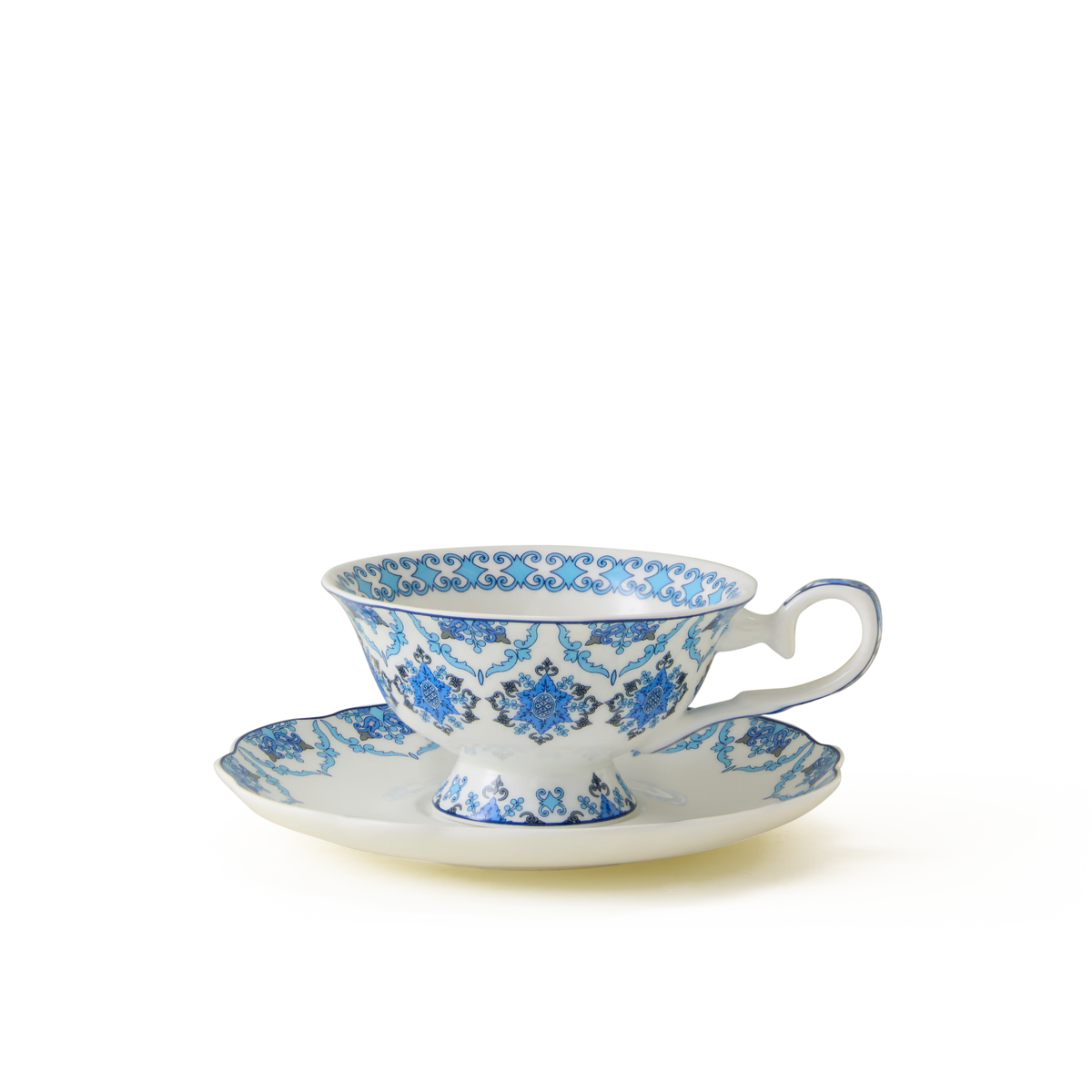 A porcelain teacup and saucer with a blue floral and scroll pattern on a white background, positioned on a plain white surface.