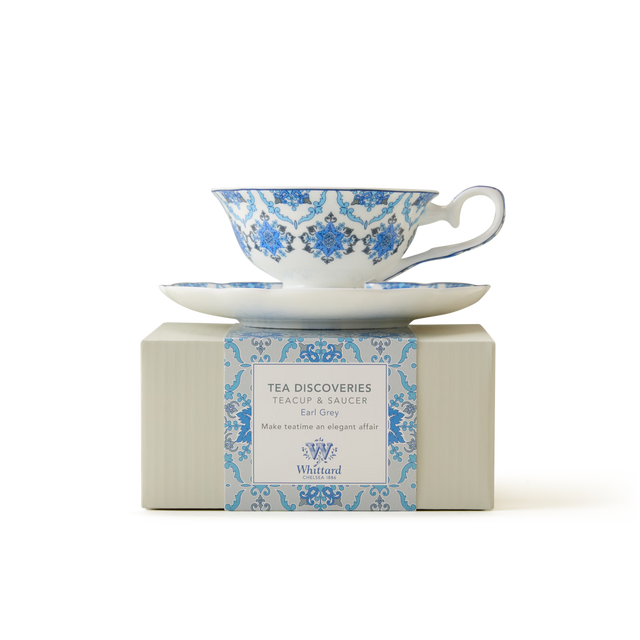 A blue and white patterned teacup and saucer sit atop a matching box labeled Tea Discoveries Teacup & Saucer Earl Grey by Whittard of Chelsea, on a plain white background.