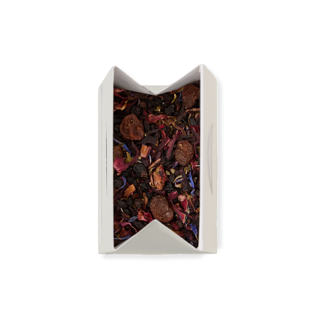 A white box of Very Berry Crush Loose Infusion, filled with loose leaf tea blended with dried fruit pieces and vibrant flower petals, viewed from above on a white background.