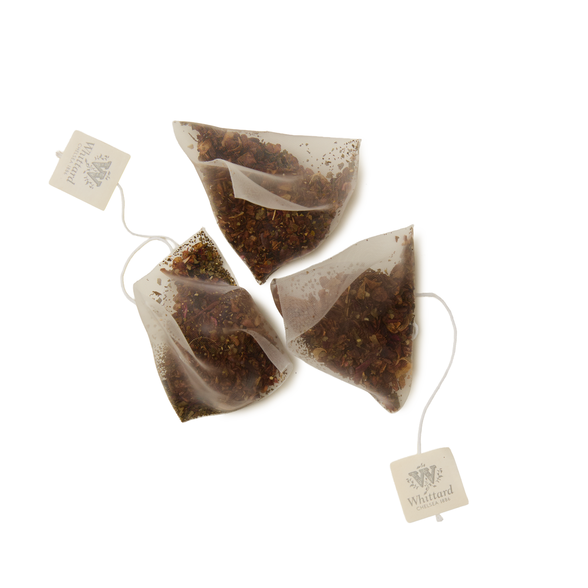 Three pyramid-shaped Cold Brew Passionfruit, Mango & Peach Infusion teabags, each filled with loose tea leaves and featuring a string with a Whittard-labeled tag, are placed on a white background.