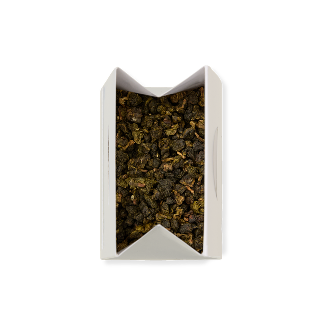 A white rectangular box with an open top, filled with Milk Oolong Loose Leaf Tea featuring dark green and brown leaves, viewed from above on a plain white background.