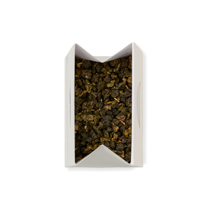 A white rectangular box with an open top, filled with Milk Oolong Loose Leaf Tea featuring dark green and brown leaves, viewed from above on a plain white background.