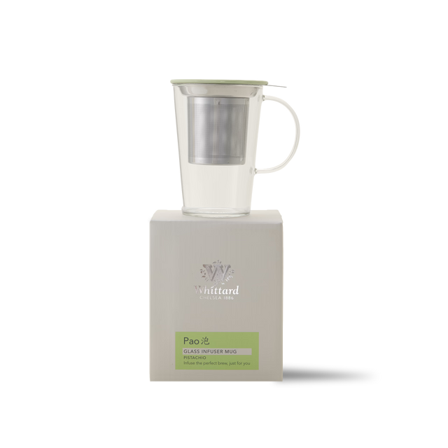 A clear glass infuser mug with a metal strainer and a light green lid, placed on top of a white Whittard Pao packaging box.