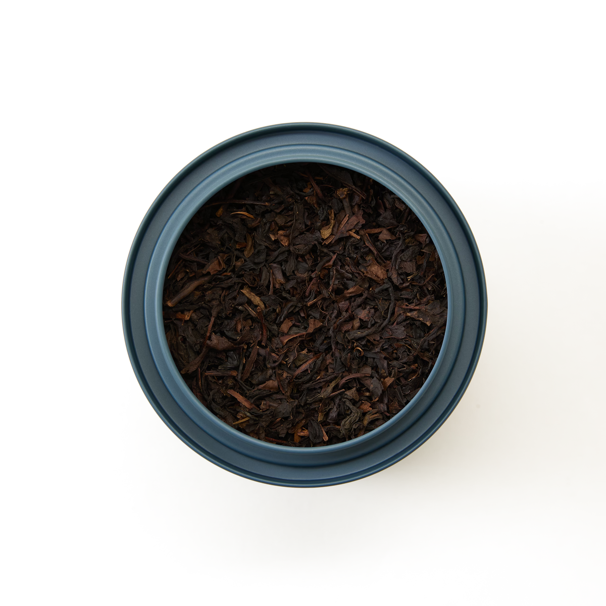 A top-down view of a dark blue container filled with Peach Oolong Loose Leaf Tea against a white background.